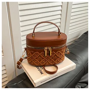Close-up of retro brown bucket bag with geometric embroidery and golden dual zippers