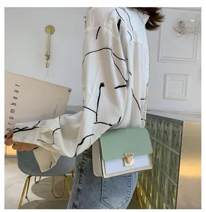 Detail shot of the two-tone crossbody bag with light green flap and gold chain strap