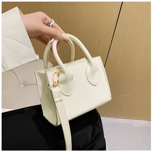 Detailed shot of white mini square crossbody bag with gold hardware and top handles