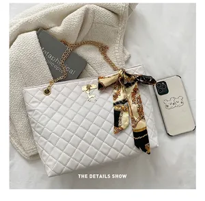 Quilted white chain tote bag detail showing interior capacity compared with a mobile phone