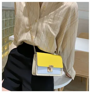 Detail of color-block mini bag with gold chain strap and heart clasp worn by model