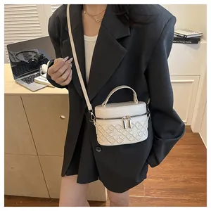 Detail view of a white embroidered quilted handbag with metal zippers and handle