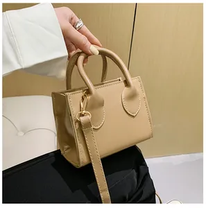 Detail of khaki mini tote bag featuring rolled handles and gold lobster claw hardware