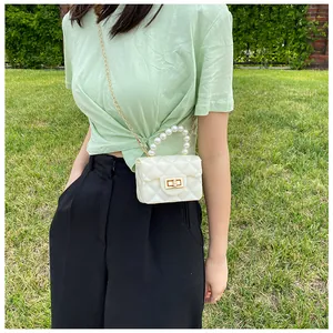 Close-up of white quilted jelly bag with faux pearl handle and gold chain strap