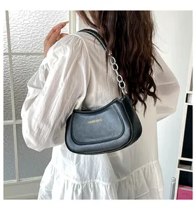 Modell mit schwarzer Halbmond-Achseltasche mit goldener Kette und gedrucktem Schriftzug