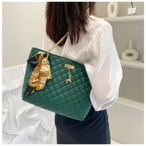 Detail view of a large dark green quilted tote bag with gold chain and printed scarf
