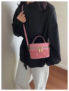 Detail of pink quilted box bag with gold double zippers and top handle worn by a model