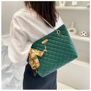 Detail of dark green quilted tote bag with gold chain strap and silk scarf accent
