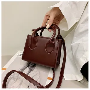 Detail view of burgundy PU leather mini handbag with gold hardware and top handles