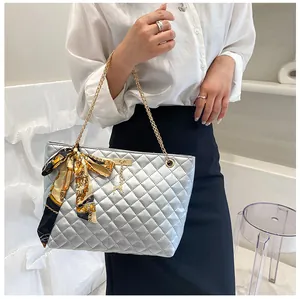 Detail of silver quilted tote bag with gold chain strap, silk scarf and animal pendant