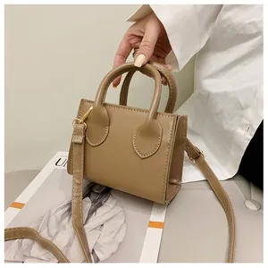 Detailed close-up of dark khaki mini square bag with golden hardware and handles