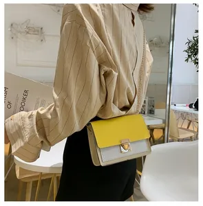 Detail of color-block flap bag with yellow accents and gold metal chain strap on model