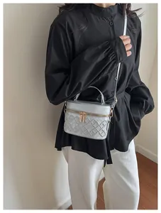 Detail view of silver quilted barrel bag featuring floral embossed patterns and metal handle