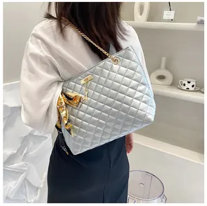 Detail of silver quilted tote bag with golden chain strap and deer charm decoration