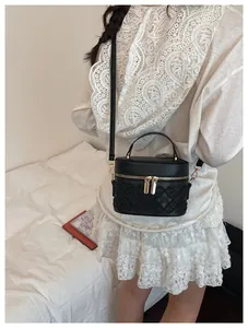 Quilted black box bucket bag with gold zipper detail shown on model in minimal room
