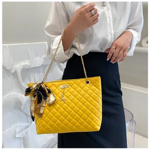Close-up of yellow quilted tote bag with golden chain strap and scarf detail