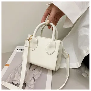 Detailed close-up of cream square handbag showing shiny leather texture and gold hardware