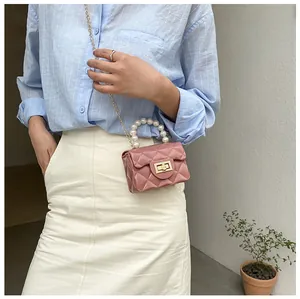 Detailed view of dusty pink mini bag with quilted pattern and large pearl handle strap