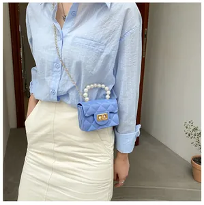 Close-up of sky blue quilted mini bag with pearl handle and golden chain on model