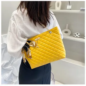Yellow quilted shoulder bag with gold chain strap and silk scarf on a model back