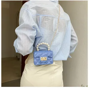 Detail of blue quilted mini bag with pearl handle and gold chain worn by a model