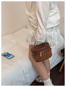 Detail of brown quilted bucket bag with golden zipper and vintage embossed pattern