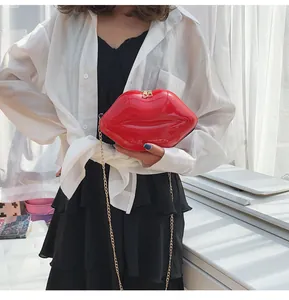 Detail of red lip-shaped crossbody bag in patent leather with gold chain strap