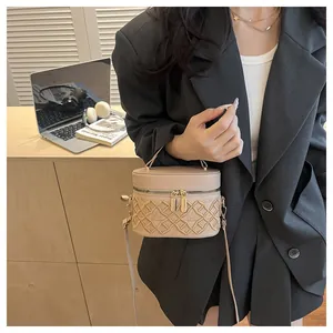 Chic beige bucket bag with quilted embroidery pattern worn by a model in a modern room