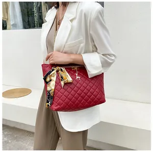 Detail of red quilted chain shoulder bag with silk scarf and gold deer charm