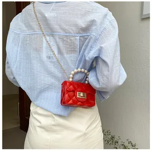 Back view of red quilted mini bag with pearl handle and gold chain on model