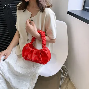 Detalle del bolso de nube rojo plisado con asa fruncida suave y acabado de textura brillante