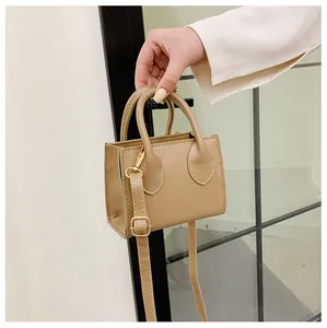 Detailed view of beige mini tote bag with adjustable long strap and gold metal hardware