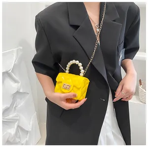 Detail of yellow quilted mini jelly bag featuring pearl handle and gold chain strap