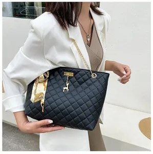 Close-up of black quilted tote bag featuring a gold deer charm and silk scarf handle