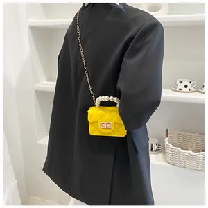 Detail view of yellow jelly bag with diamond lattice pattern and pearl handle