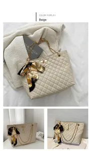 Detail of beige quilted tote bag featuring golden chain handles and decorative silk scarf