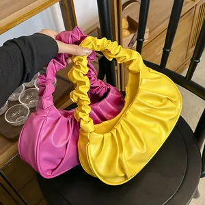 Detalle de bolsos de nube plisados en amarillo vibrante y rosa fucsia en estante