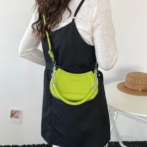 Neongrüne Halbmond Schultertasche mit silberner Kette an Model präsentiert