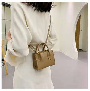 Mini khaki square handbag shown on model with adjustable strap and dual handles