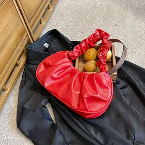 Detalle del bolso de nube roja plisado con un elegante asa redonda de madera
