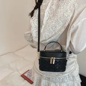 Elegant black embroidered cylinder bucket bag with gold zippers and crossbody strap