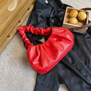 Detalle de bolso rojo fruncido estilo nube en piel sintética sobre fondo de satén negro