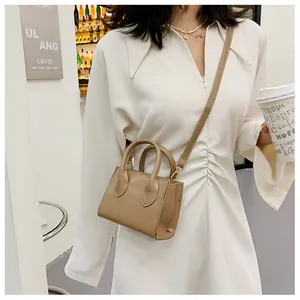 Close-up of khaki mini handbag with gold hardware and shoulder strap in cafe setting