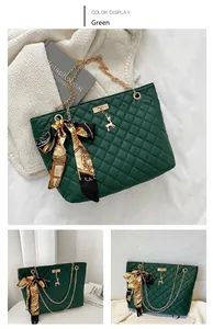 Detail of emerald green quilted handbag with gold deer charm and floral silk scarf