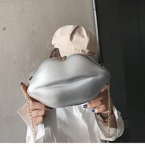 Lip-shaped silver metallic mini bag with golden chain strap shown in a fashion street style