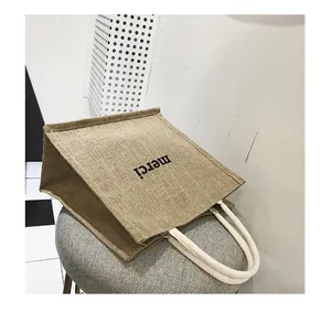 Dettaglio della borsa tote in iuta con stampa merci e manici in corda di cotone su sgabello
