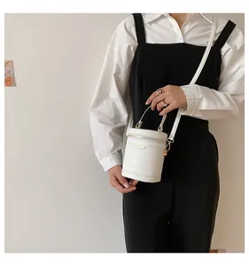 Detailansicht der weißen Zylindertasche mit Krokostruktur, Goldzipper und Kaka-Bags-Logo