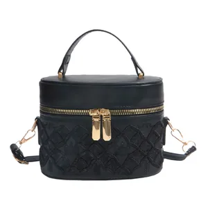 Quilted black cylinder handbag with gold double zippers and top leather handle
