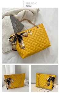 Close-up of yellow quilted tote bag with silk scarf and gold deer charm detail