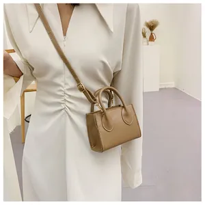 Mini khaki square leather handbag with gold hardware and shoulder strap shown on model